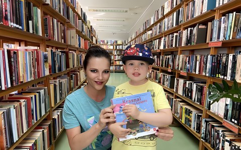 Dziecko i bibliotekarka prezentują książkę