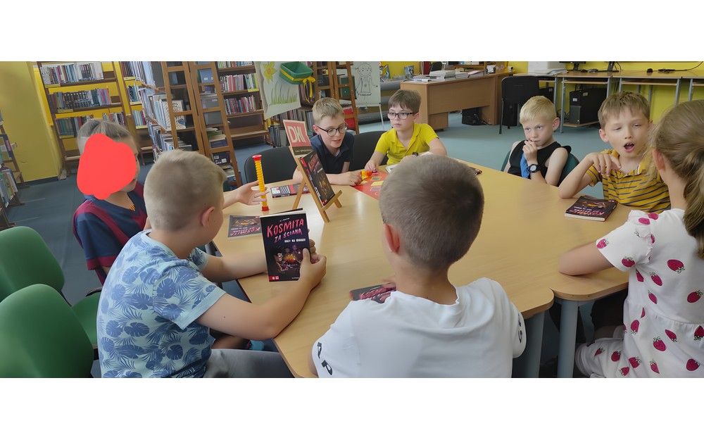 dzieci siedzą przy stole i dyskutują o przeczytanej książce