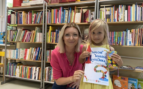 Dziewczynka pozuje z dyplomem i bibliotekarką