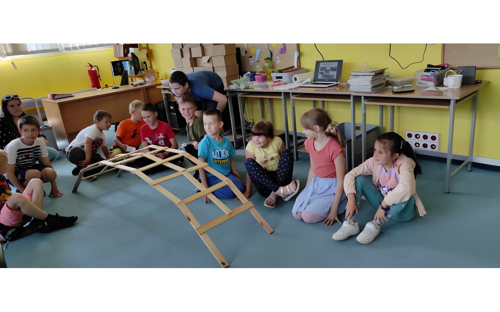 dzieci z prowadzącymi zajęcia budują drewniany most