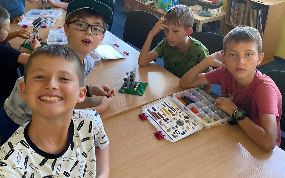 Dzieci pozują do zdjęcia z konstrukcją z klocków