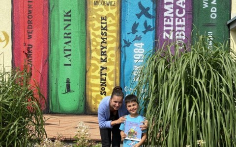Chłopiec i bibliotekarka prezentują książeczkę