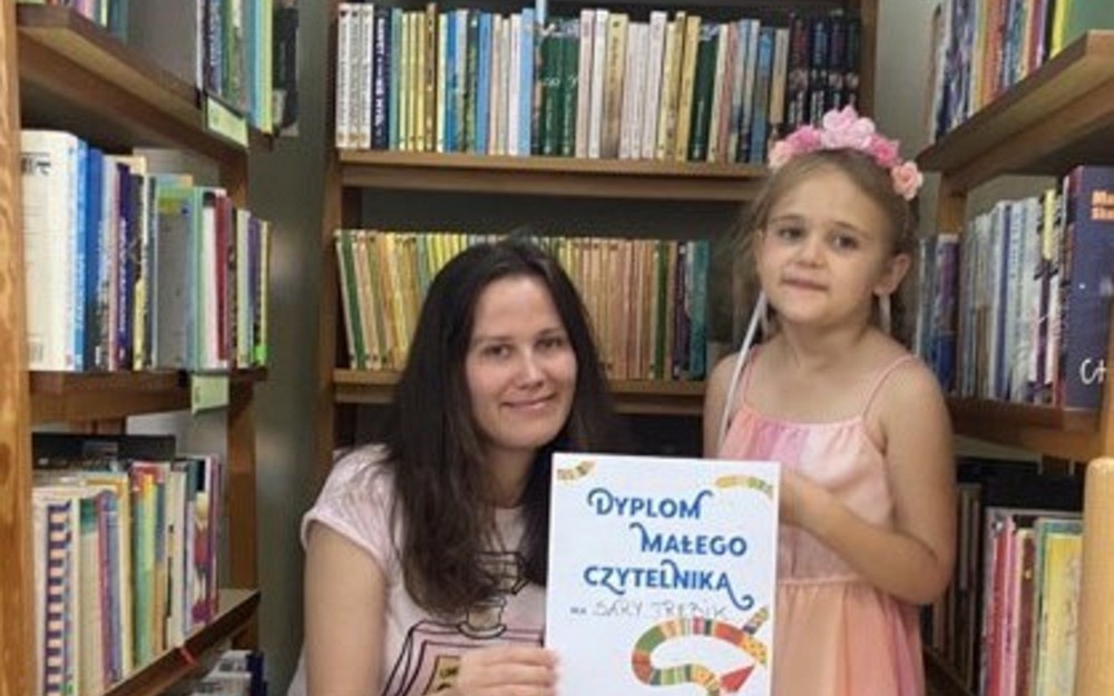 Dziewczynka z bibliotekarką prezentują dyplom