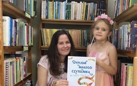 Dziewczynka z bibliotekarką prezentują dyplom