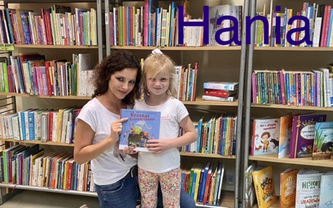 Dziecko i bibliotekarka prezentują książkę