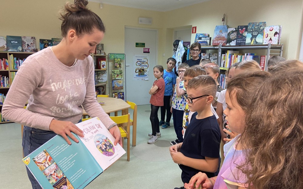 Bibliotekarka pokazuje dzieciom stronę tytułową książki
