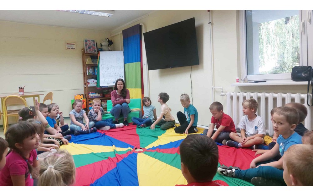 Dzieci siedzą na kolorowej chuście i rozmawiają o jesieni