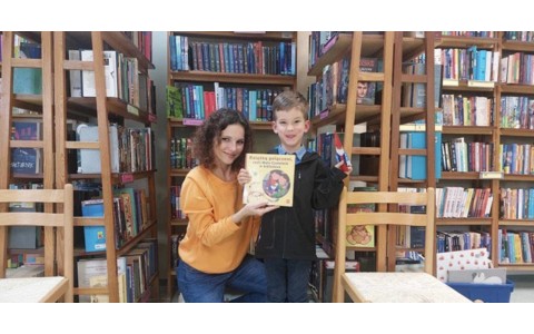 Chłopiec i bibliotekarka prezentują książeczkę