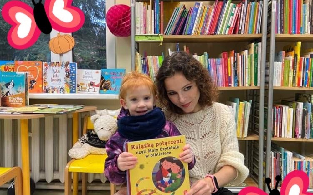 Dziewczynka z bibliotekarką prezentuje książeczkę
