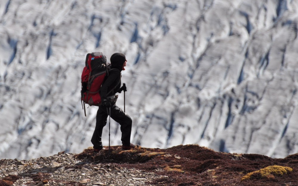 Zdjęcie podróżniczki w trakcie trekkingu górskiego.