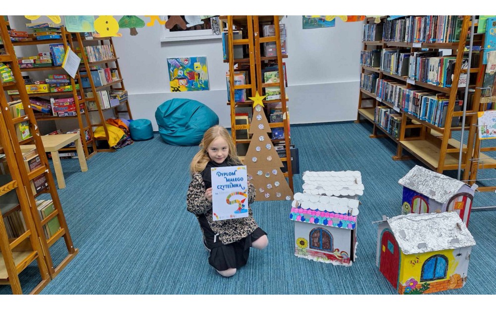 dziewczynka pozuje z dyplomem małego czytelnika