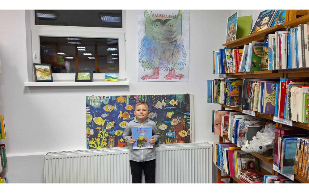 chłopiec pozuje do zdjęcia z pakietem 'Mała Książka, Wielki Człowiek