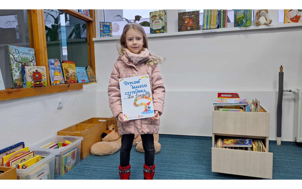 dziewczynka pozuje do zdjęcia z dyplomem "Mała Książka, Wielki czlowiek"