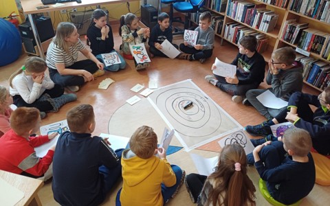 Na zdjęciu rozpoczęcie zajęć z Panią Beatą Piwar - dzieci i prowadząca siedzą na podłodze w kręgu.