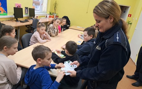 Policjantka wręcza dzieciom naorody za udział w konkursie.