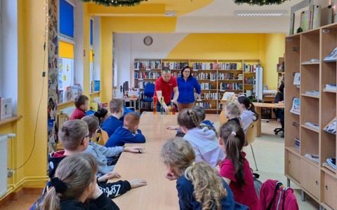 Na zdjęciu feriowicze siedzą przy stołach i czekają na pierwsze doświadczenie w wykonaniu właścicieli Pomysłowej Fabryki