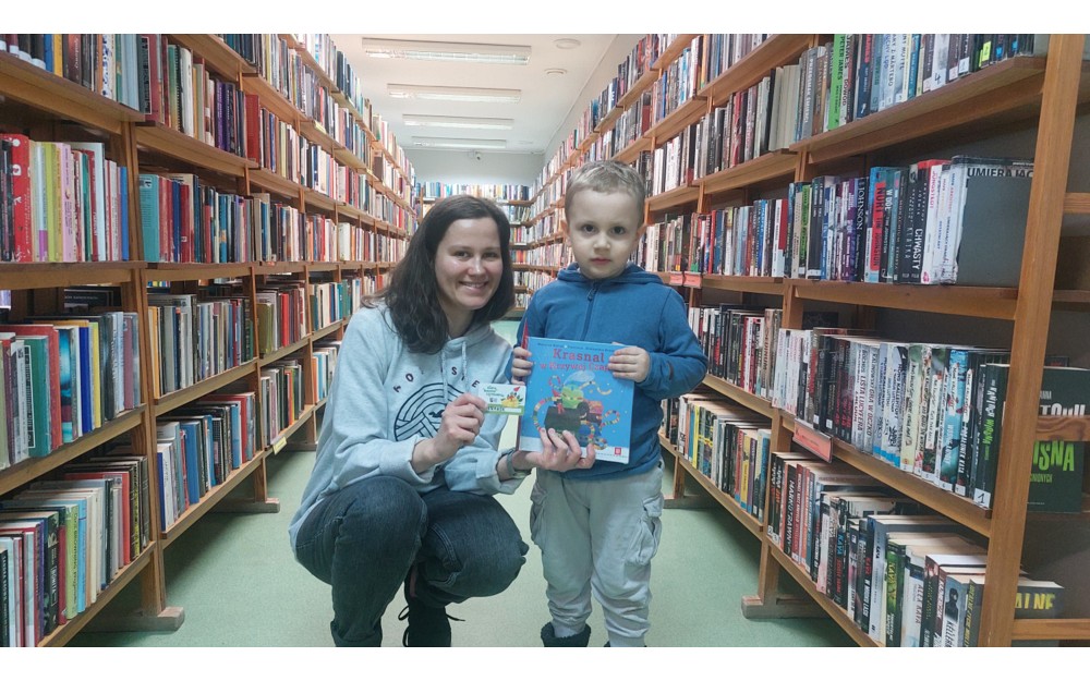 Bibliotekarka i chłopiec prezentują książeczkę