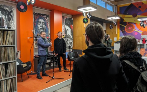 Wernisaż Dariusza Kozłowskiego, widok na scenę Mediateki na której stoi dyrektor KBP Dariusz Pawlikowski i Dariusz Kozłowski, na pierwszym planie stoją goście wernisażu