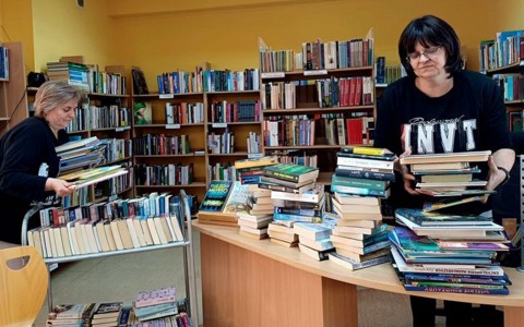 Na zdjęciu Ewa i Wiola porządkujące stosy książek oddane przez czytelników