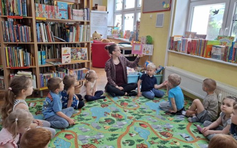 Dzieci siedzą w kole, bibliotekarka czyta książkę "Kicia kocia w bibliotece"