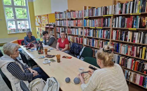 Panie z "Robótkowa" siedzą przy stole rozmawiają i robią na drutach
