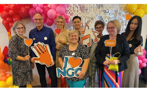 Fotografia przedstawia grupę bibliotekarzy działającą w strukturach SBP. Osoby na zdjęciu trzymają w dłoniach gadżety z fotbudki promujące wydarzenie. W tle znajdują się kolorowe balony