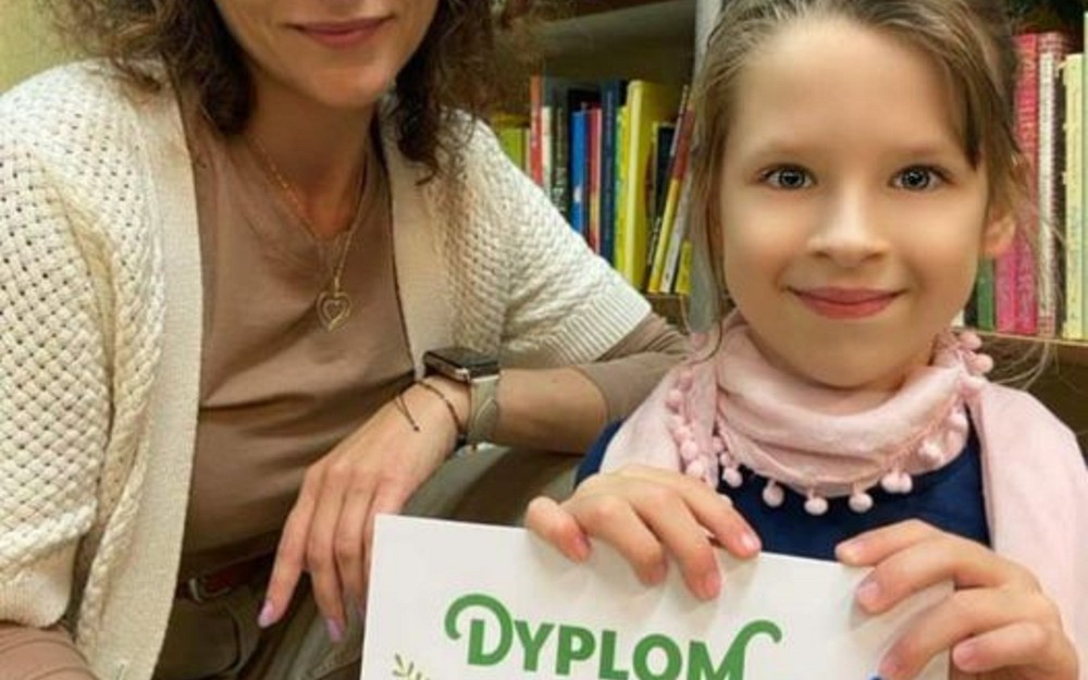 Bibliotekarka i dziewczynka prezentuje dyplom