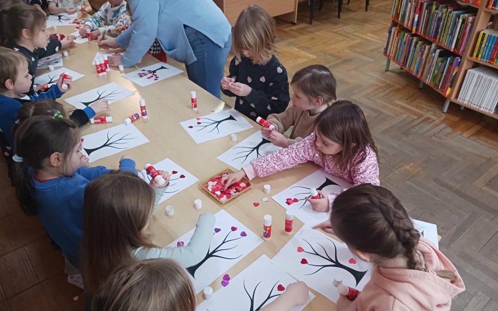 Dzieci wykonują drzewka miłosne stojąc przy stole