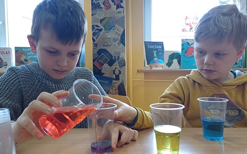 Na zdjęciu uczestnicy zajęć mieszają kolory