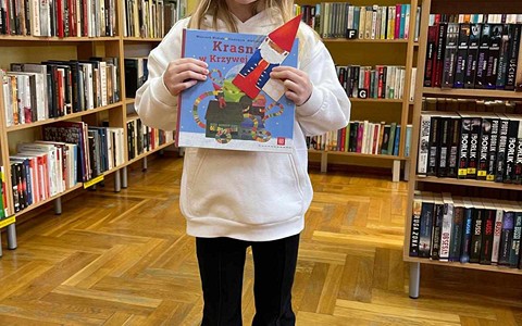 Dziewczynka uśmiecha się stojąc z pakietem z akcji "Mała książka-Wielki człowiek"