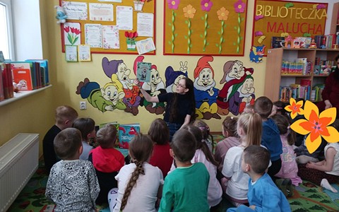 Bibliotekarka czyta dzieciom książkę, dzieci siedzą w kole