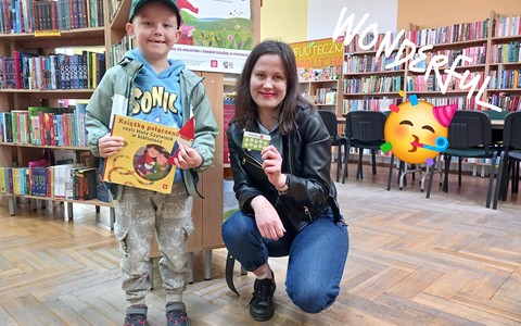 Bibliotekarka z chłopcem trzymają książkę i kartę biblioteczną