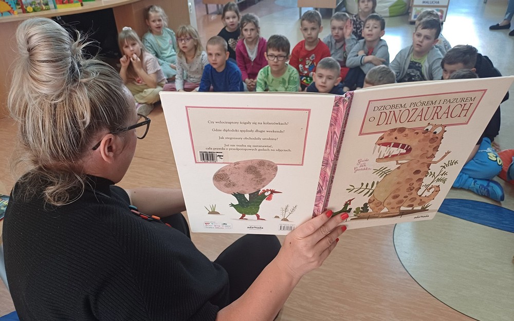 Na zdjęciu Gosia czyta przedszkolakom książkę o dinozaurach