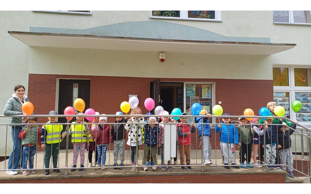 Na zdjęciu grupa PSZCZÓŁEK pozuje z balonami przed naszą biblioteką