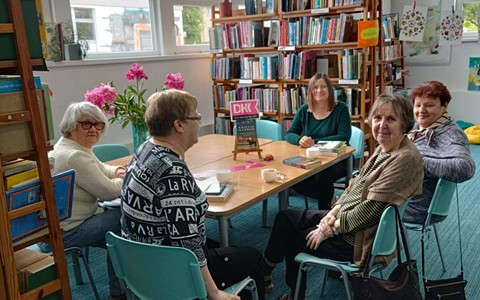 panie siedzą przy stole i dyskutują o przeczytanej książce z bibliotekarką