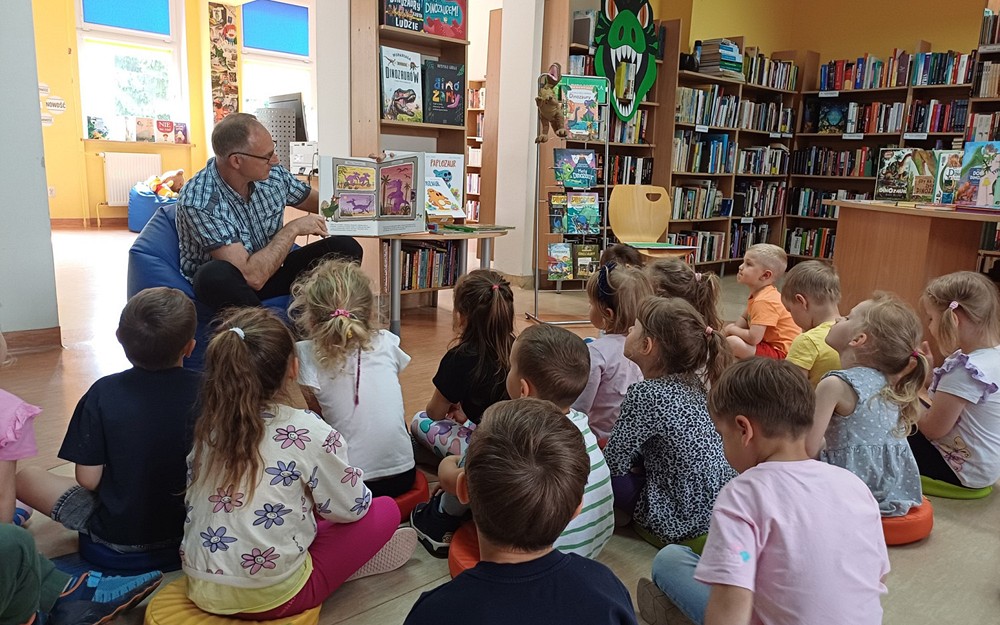 Na zdjęciu nasz gość Piotr Saporowski czyta przedszkolakom książeczkę o dinozaurach