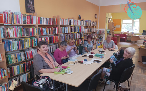 Panie siedzą przy stole i szydełkują