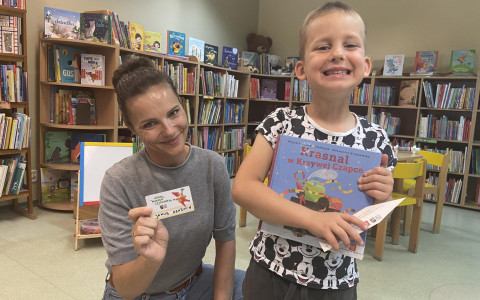 Bibliotekarka i dziecko prezentują książeczkę