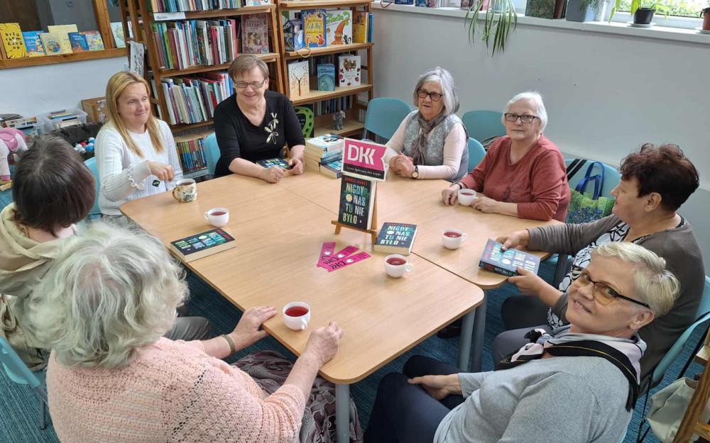 panie siedzą przy stole i dyskutują o przeczytanej książce z bibliotekarką