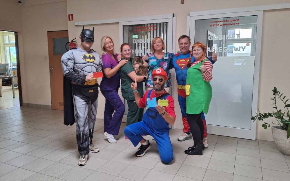 SuperBohaterowie pozują do zdjęcia z personelem hospicjum i kotem