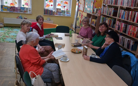 Bibliotekarka wraz z czytelniczkami omawia książkę "Wojenne serca"