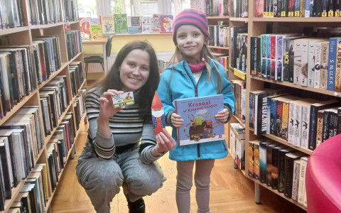 Bibliotekarka pozuje z dziewczynką i pokazuje kartę z programu Mała Książka - Wielki Człowiek