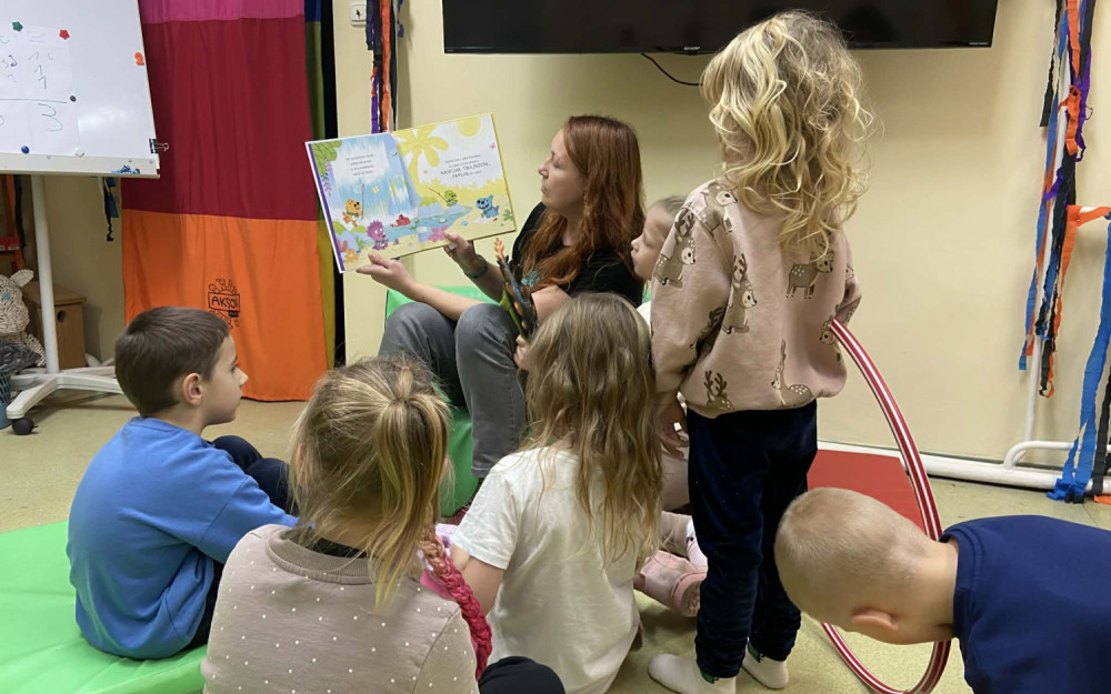 Bibliotekarka czyta książeczkę dzieciom