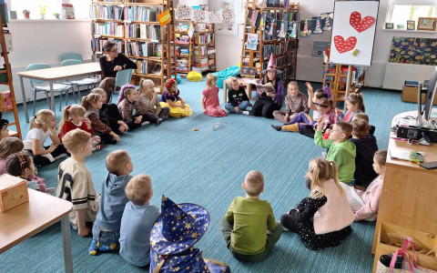 bibliotekarka w stroju czarownicy czyta dzieciom książkę