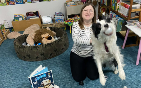 bibliotekarka pozuje do zdjęcia z psem, który łapie piłki