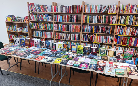 Stół na którym leżą książki, w tle regały z książkami