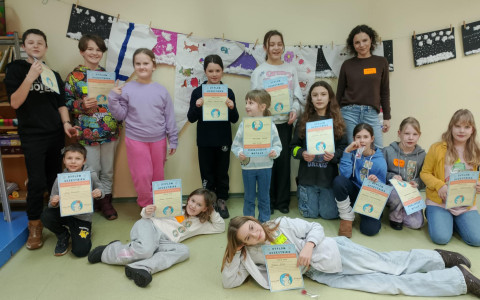 dzieci wraz z bibliotekarką pozują do zdjęcia. Każde dziecko trzyma dyplom