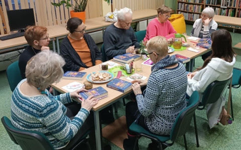 Uczestnicy Dyskusyjnego Klubu Książki rozmawiają przy stole o książce Witajcie w księgarni Hyunam-Dong