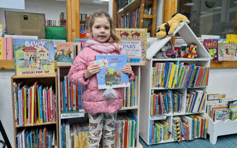 Dziewczynka pozuje do zdjęcia ze swoim pakietem "Mała Książka, Wielki Człowiek"