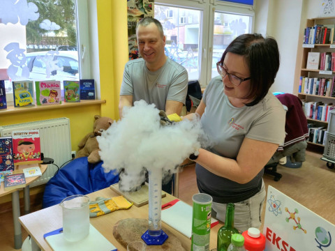 Na zdjęciu pani Kinga i pan Tomek, czyli Pomysłowa Fabryka przy stole z menzurkami i innymi przedmiotami potrzebnymi do doświadczeń z azotem.